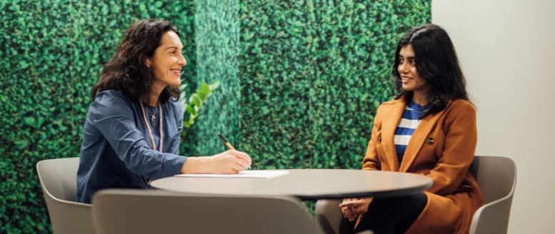 Two women talking at a desk