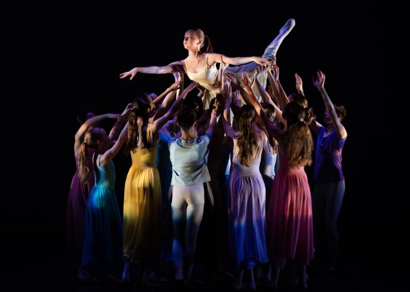 Irish National Youth Ballet dancers performance on stage in ballet performance attire, one dancer is lifted overhead with group of dancers supporting underneath.