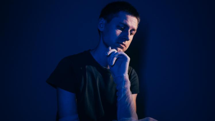 Person sitting with holding chin in hand whilst wearing a clear glove