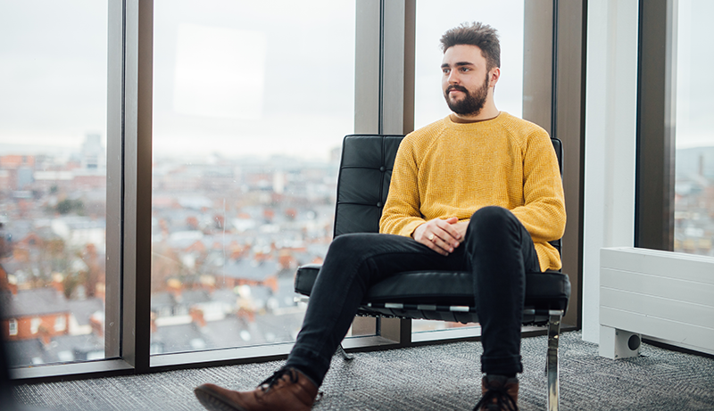 Student sitting in Wellbeing Room, Main Site Tower, looking through the window.