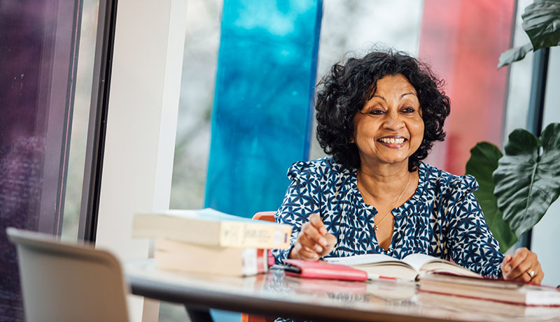 Lecturer with books, sitting at table, in Computer Science Building