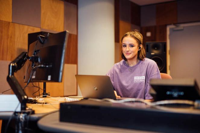 Image of Georgina in Broadcast Production Studio using her laptop