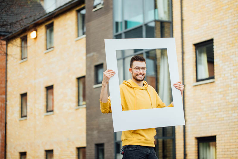 Image of Philip holding large polaroid frame outside Elms BT9 