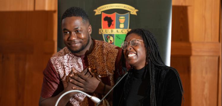 Two smiling students at podium in QUB Great Hall for Black History Month 2021