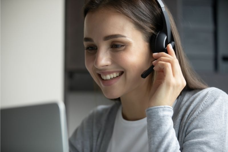 smiling young woman with headset looking at a laptop