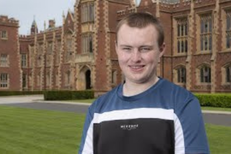male student standing smiling outside Queen's University Belfast