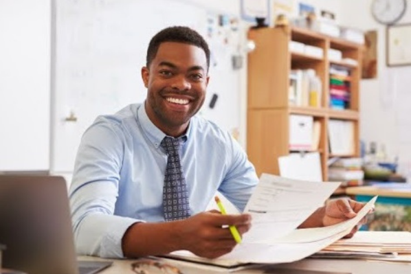 young business man sitting at desk smiling