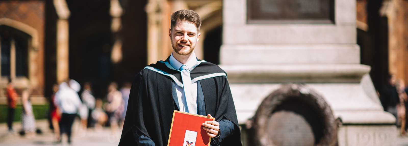 male student in graduation gown outside Queen's University
