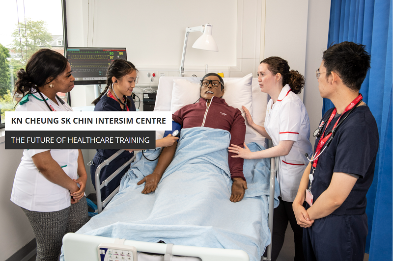 A group of student or young nurses standing around a simulated patient in a hospital bed