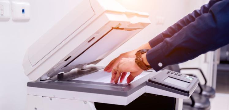 Image of hands placing a page into an MFD printer