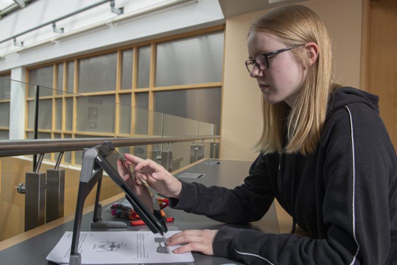 A visually impaired student in the library using assistive technology.