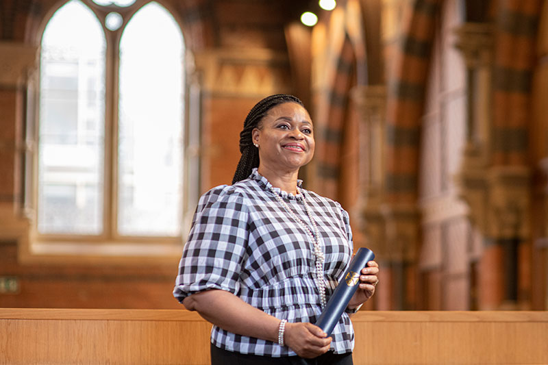 Scholarship recipient in the graduate school holding a scroll holder