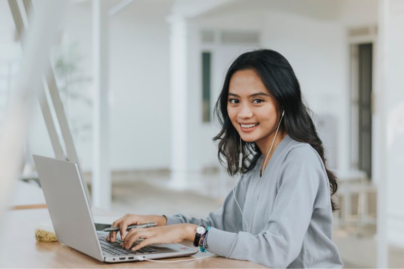 student or young woman using laptop in bright open indoor space