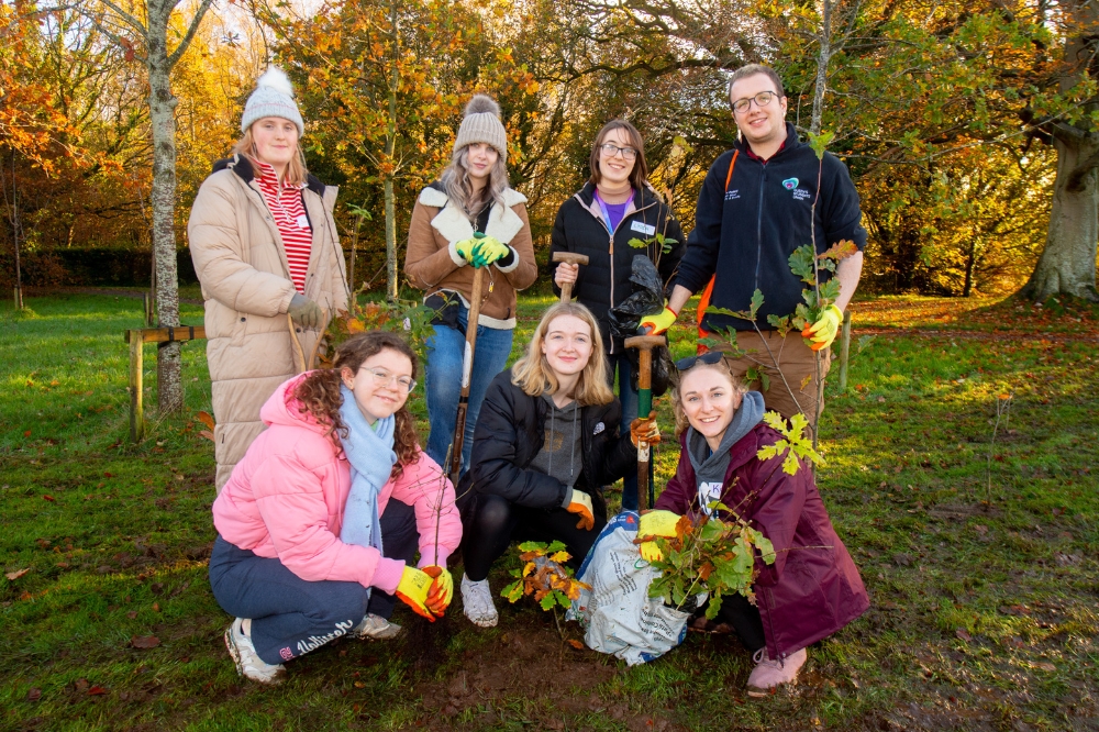 student volunteers helping to plant saplings at Malone Playing Fields