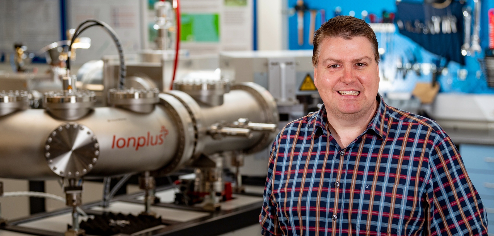 Professor Graeme Swindles standing the radiocarbon accelerator in the 14CHRONO lab at Queen's University Belfast