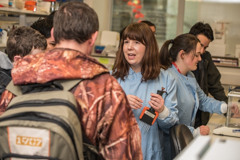 researchers and technicians showing people around a cancer laboratory