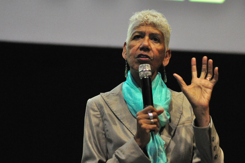 human rights advocate Ericka Huggins speaking into a microphone