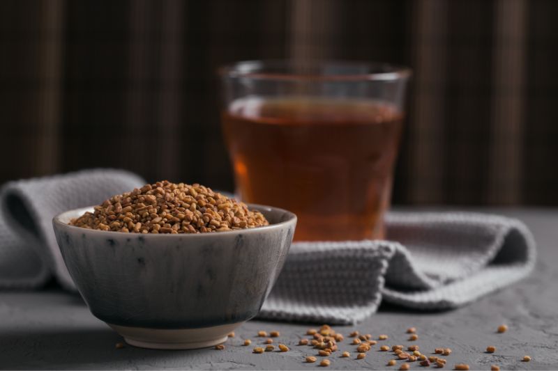 pot of fenugreek beside glass teacup filled with black tea