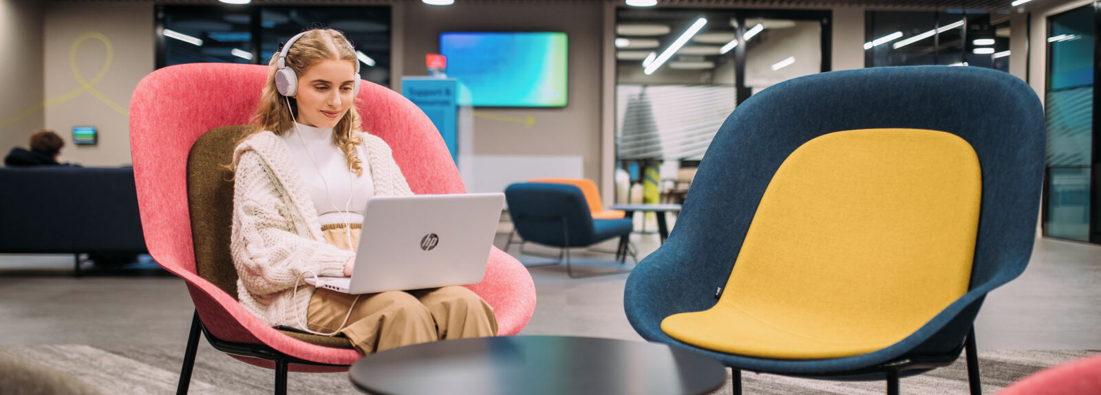 Student in a comfy chair on a laptop with headphones