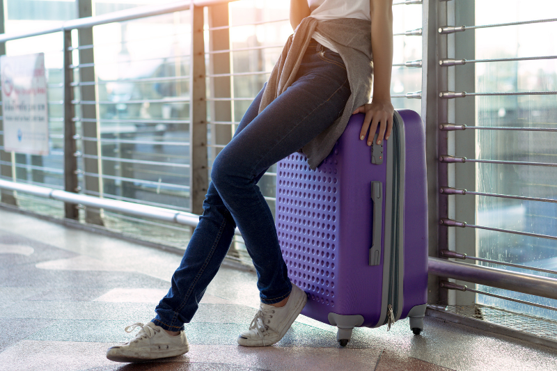 Person leaning on a purple suitcase