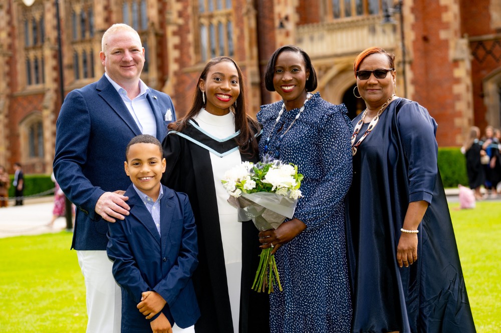 female graduate posing with her family at graduation