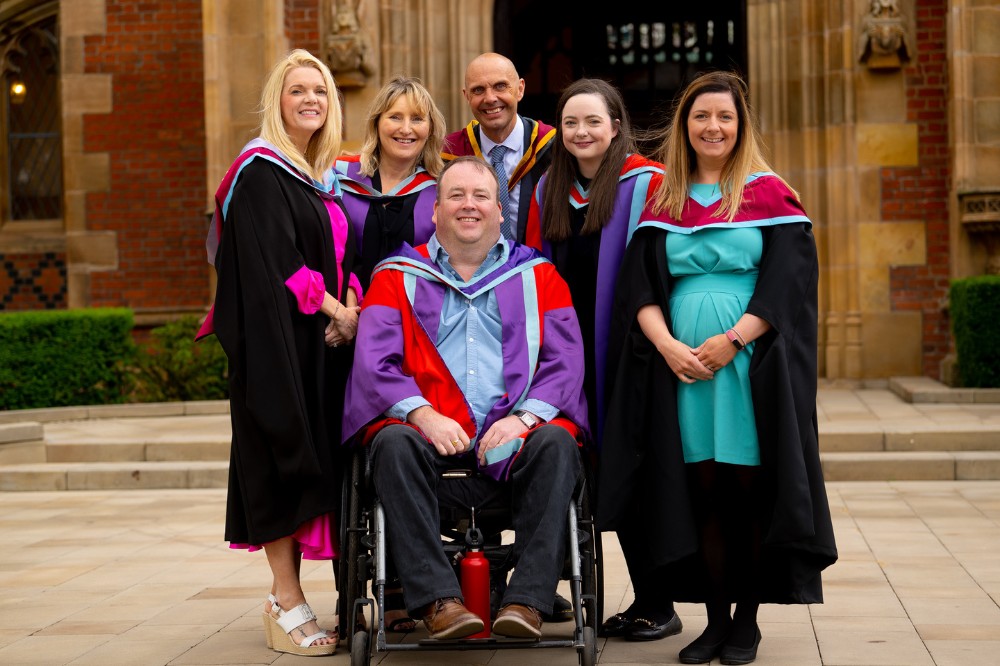 group of School of Nursing and Midwifery staff in graduation gowns outside the Lanyon Building