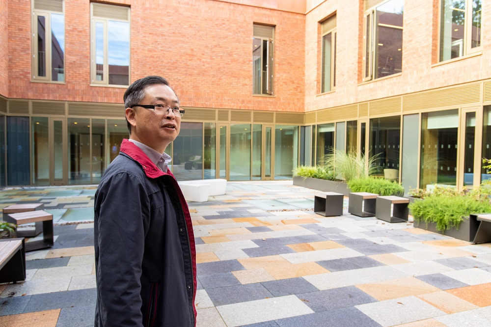 Liang Wang, staff member, taking in the view of the inner courtyard in Queen's Business School