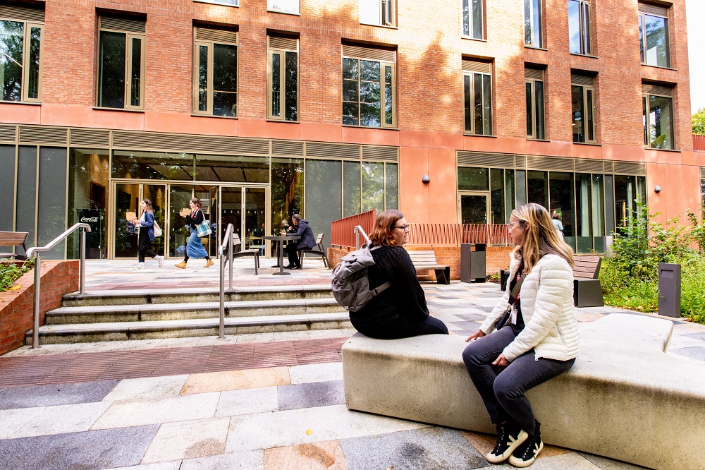 staff / students chatting in seating area outside Queen's Business School