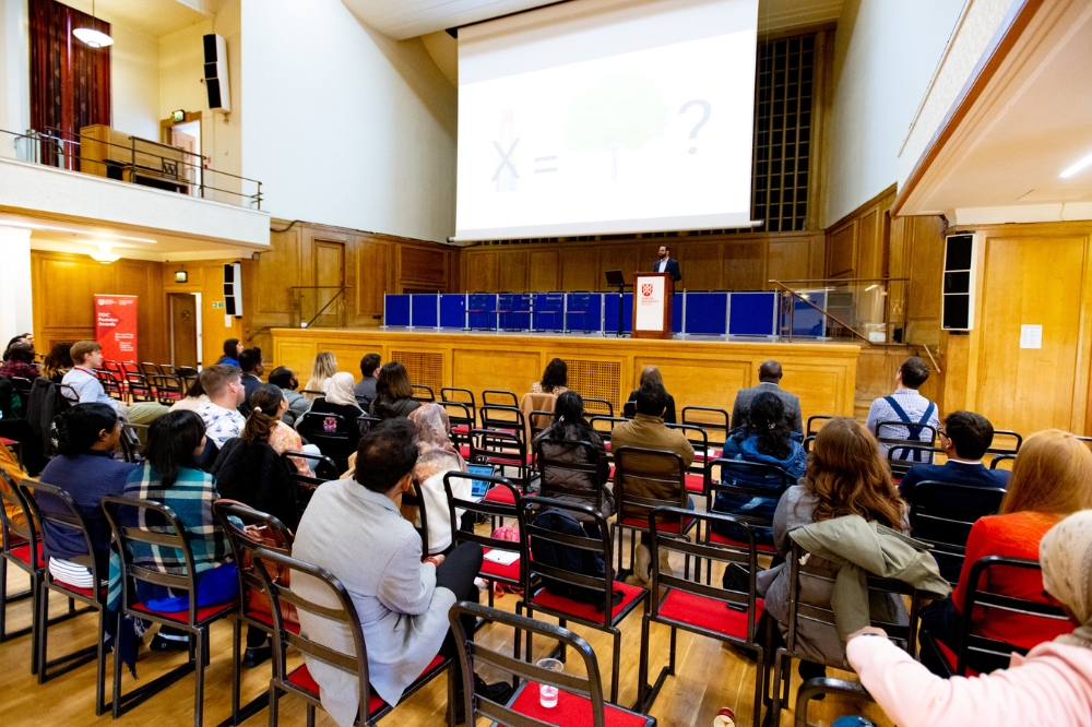 group of postdocs and research staff listening to a presentation at Queen's Postdoc Showcase 2023 in the Whitla Hall