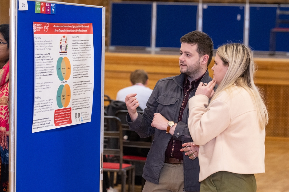 two postdocs discussing an academic poster at the poster presentation at Queen's Postdoc Showcase 2023