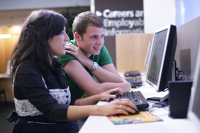 male and female student working on a computer together