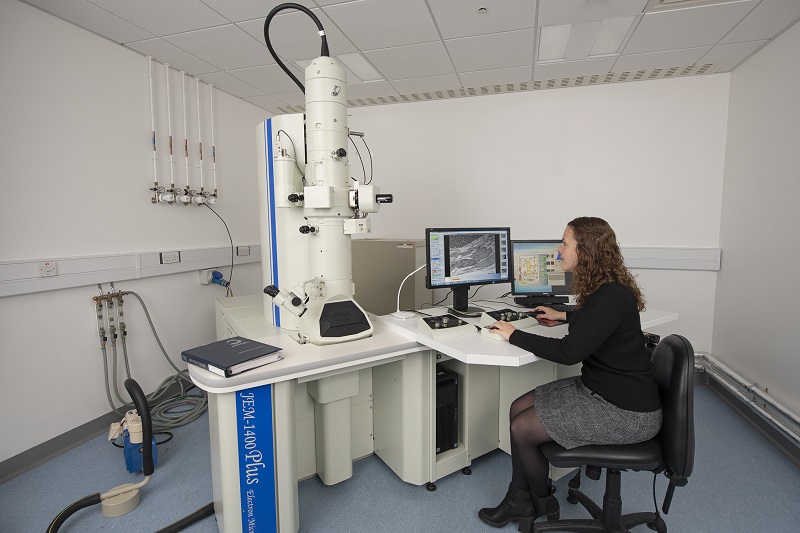 Girl analysing micropscope images at computer in lab