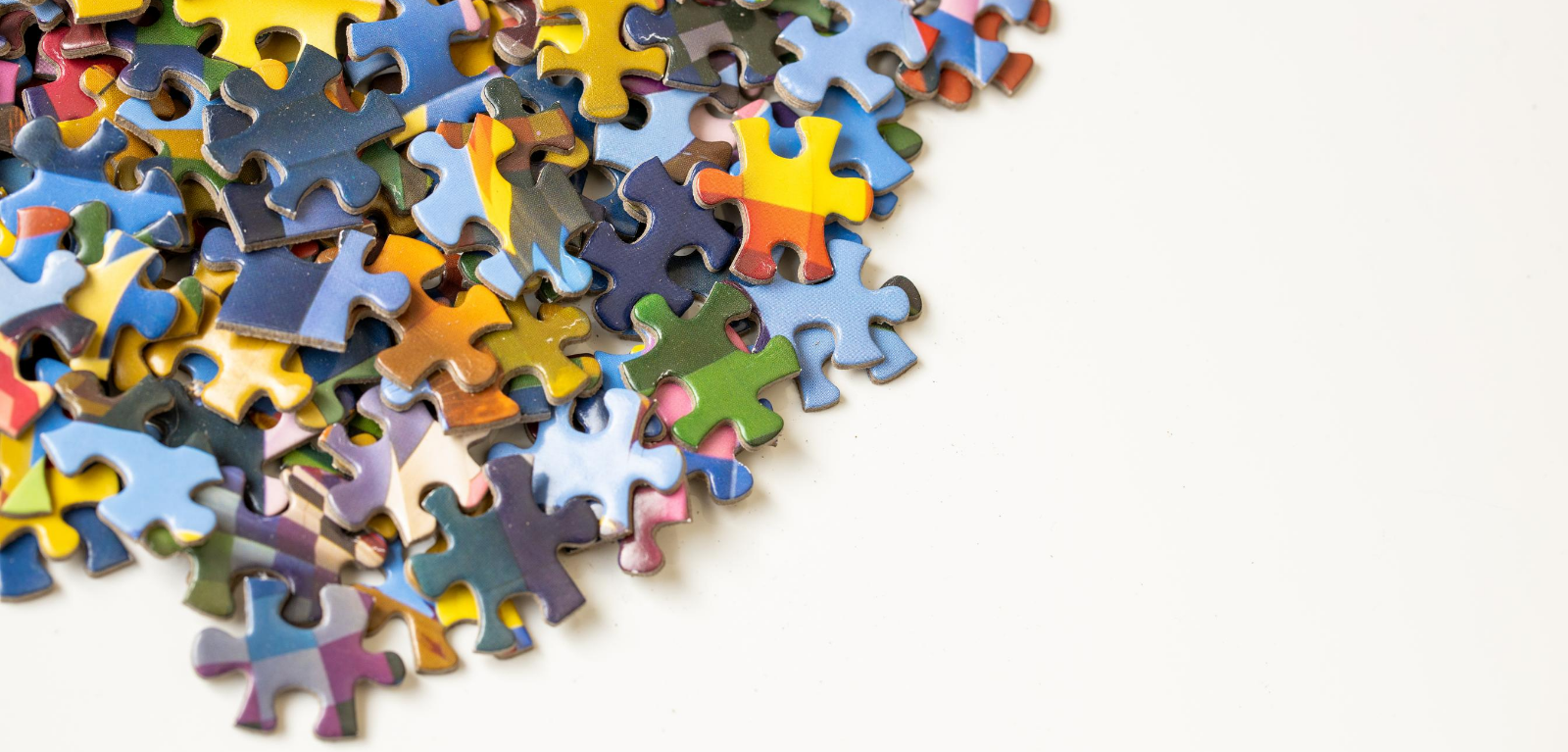 Photograph of multicoloured jigsaw puzzle pieces on white background