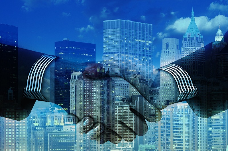 ghosted image of a handshake over a skyscraper background
