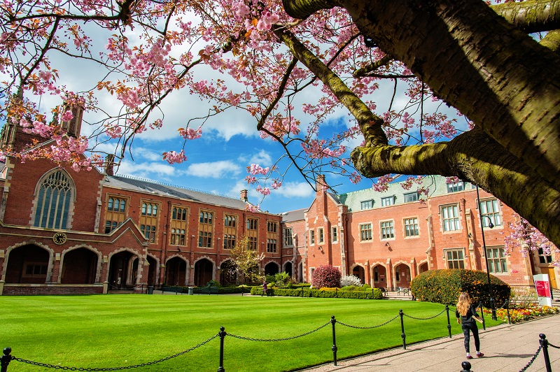 A student walking through the Lanyon Quad on a sunny day.