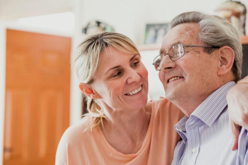 woman smiling at a smiling elderly man in a home setting