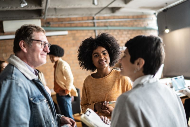 man and two women chatting informally at an indoor event or training / breakout session