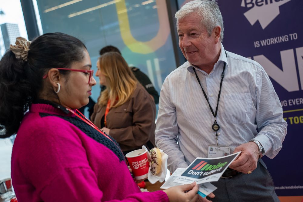 Staff member speaking with a student while handing out a leaflet about violence prevention.
