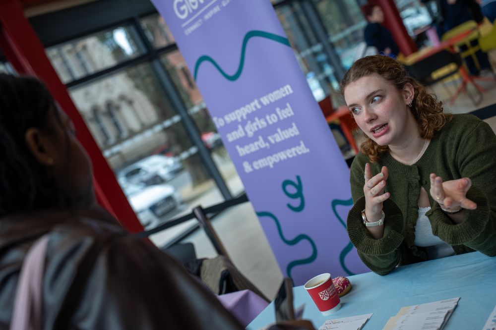 Student speaking with a representative at a campus information table about support services.