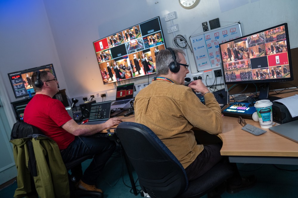 two men monitoring audiovisual equipment behind the scenes at an event
