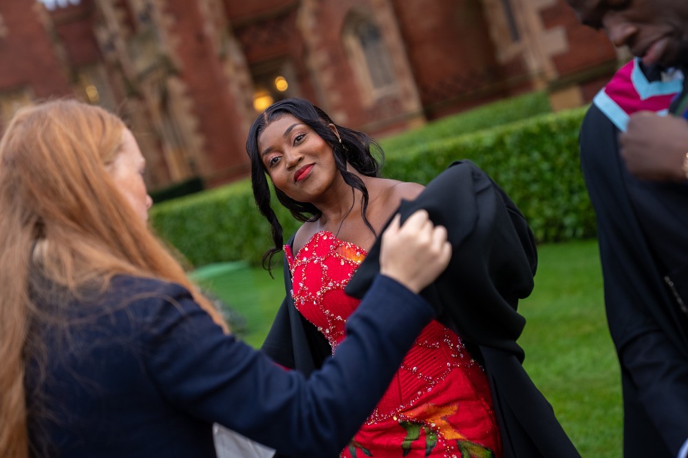 young black woman in red dress being helped with her graduation robe